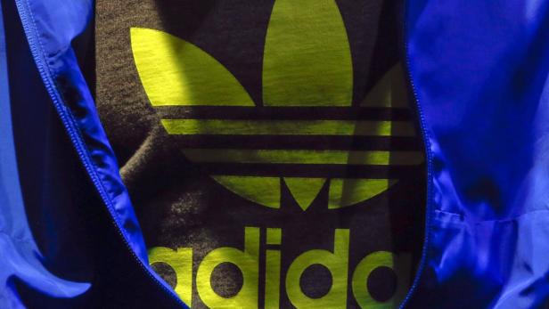 Ein Adidas-T-Shirt mit großem Logo unter einer geöffneten blauen Jacke.
