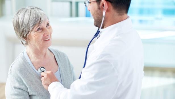 Ein Arzt untersucht eine ältere Patientin mit einem Stethoskop.
