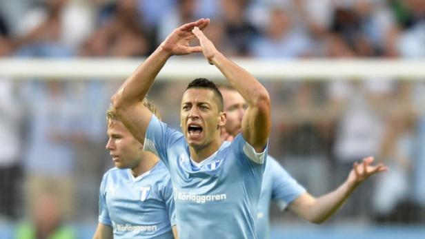 Ein Fußballspieler jubelt mit erhobenen Armen auf dem Spielfeld.