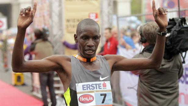 Ein Marathonläufer mit der Startnummer 7 jubelt mit erhobenen Armen.