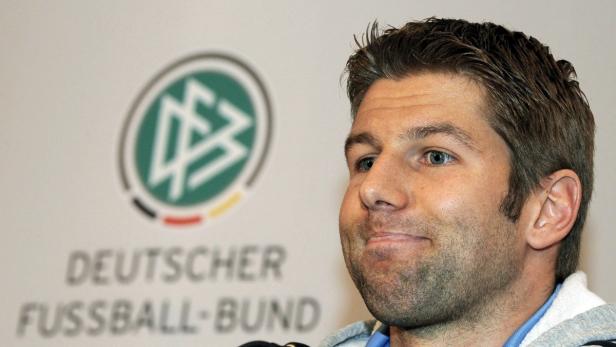 Ein Mann steht vor dem Logo des Deutschen Fußball-Bundes.