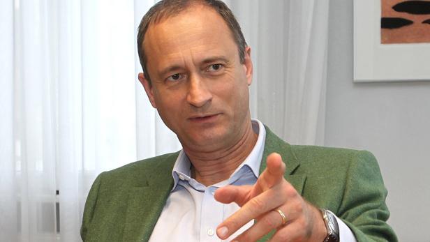 Ein Mann mit grünem Sakko zeigt mit dem Finger nach vorne.