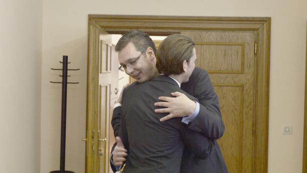 Zwei Männer in Anzügen umarmen sich in einem Büro.