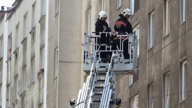 Zwei Feuerwehrleute stehen in einem Hubsteiger vor einem Wohnhaus.