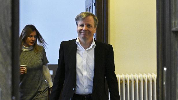 Ein Mann in Anzug und eine Frau mit Kaffee betreten einen Raum.