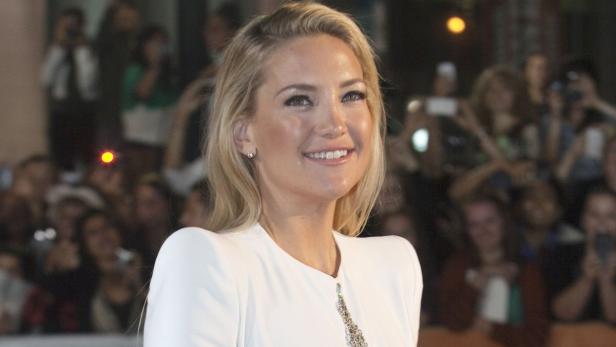 Kate Hudson lächelt auf einem roten Teppich in die Kamera.
