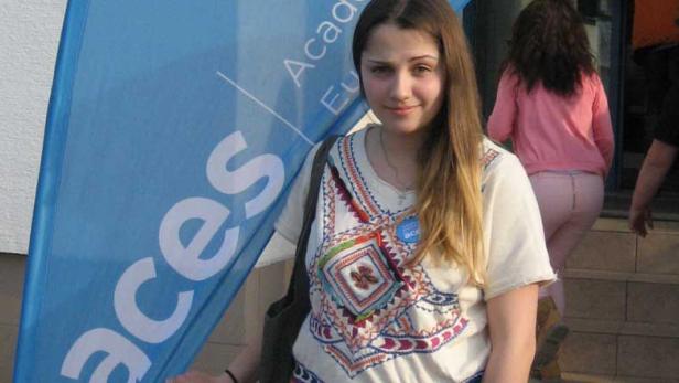 Eine junge Frau steht vor einem blauen ACES-Banner.