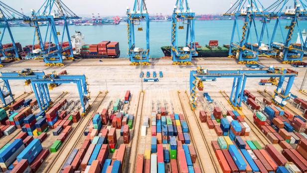 Ein Containerhafen mit zahlreichen bunten Containern und blauen Kränen.