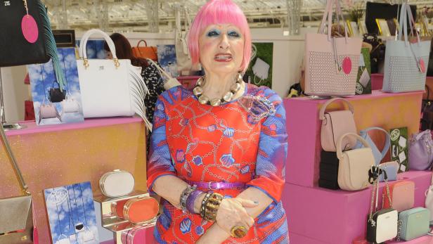 Zandra Rhodes posiert vor einer Auswahl ihrer Handtaschen.