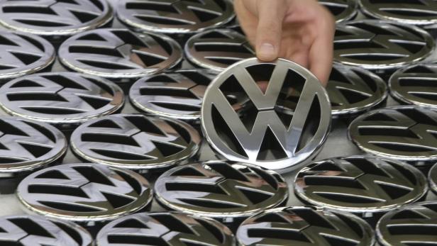 File picture shows an employee posing with an emblem for a Volkswagen Golf car during a photocall in a production line at the Volkswagen headquarters in Wolfsburg November 14, 2008. German carmaker Volkswagen is poised to unveil another record profit and limit bonuses for management, further highlighting the gaping divide among Europe&#039;s mass-market auto manufacturers. Picture taken November 14, 2008. REUTERS/Christian Charisius/File (GERMANY - Tags: TRANSPORT BUSINESS)