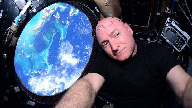 Ein Astronaut macht ein Selfie vor einem Fenster mit Blick auf die Erde.