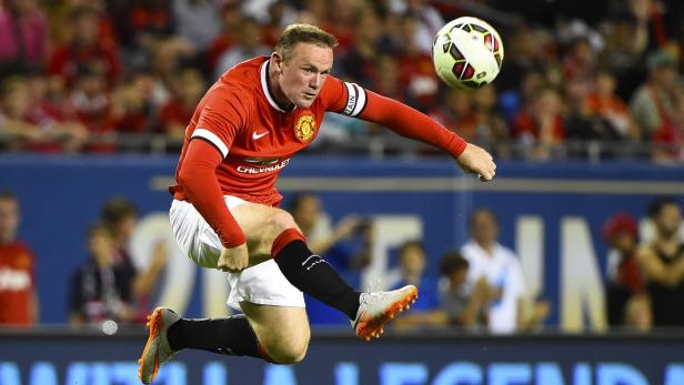 Wayne Rooney springt, um einen Fußball zu treten.