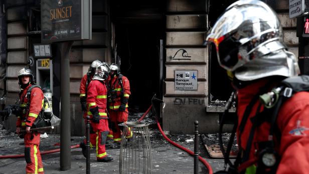 Firefighters stand at the entrance of a burnt Tarneaud Bank near the Champs-Elysees avenue, during clashes with riot police forces during a demonstration by the "yellow vests" movement in Paris