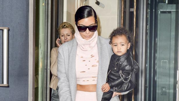 Kim Kardashian trägt ihr Kind in einer schwarzen Lederjacke.