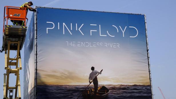 Ein Arbeiter montiert ein großes Werbeplakat für Pink Floyds „The Endless River“.