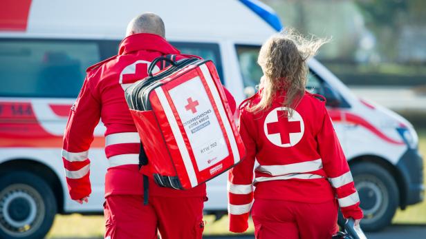 Zwei Sanitäter des Roten Kreuzes gehen zu einem Rettungswagen.