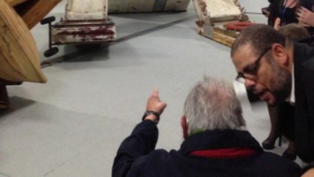 Zwei Männer betrachten alte Flugzeugteile in einer Ausstellungshalle.