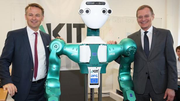 Werner Pamminger, Leiter von Business Upper Austria, und Landeshauptmann Thomas Stelzer (re.) mit einem Roboter.