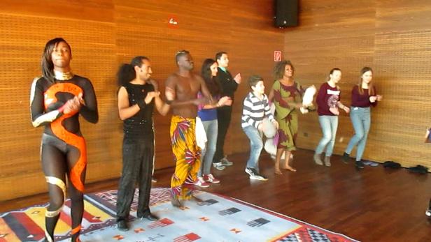 Eine Gruppe von Menschen tanzt in einem Raum mit Holzwänden.