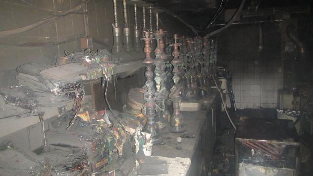 Ein Raum mit starken Brandschäden und einer Reihe von Wasserpfeifen.