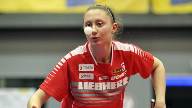 Eine Tischtennisspielerin balanciert einen Ball auf ihrem Gesicht.