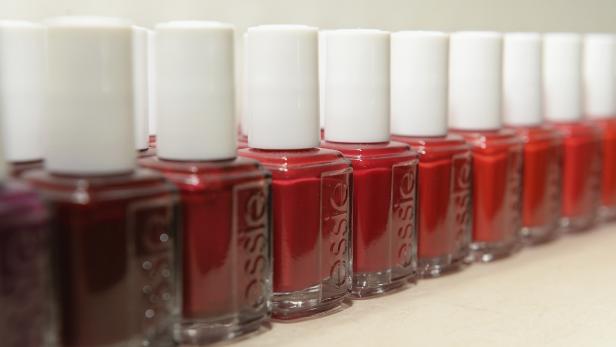 Eine Reihe von roten Essie Nagellackflaschen mit weißen Deckeln.