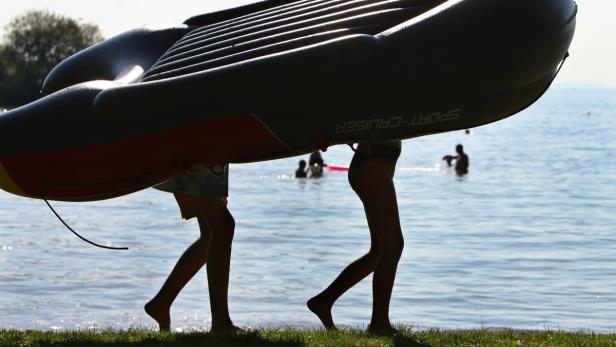 Zwei Jugendliche tragen am Samstag (20.08.2011) am Badestrand eines Campingplatzes in Lindau (Schwaben) ein Schlauchboot zum Wasser. Ideales Strand- und Badewetter herrscht derzeit am Bodensee. Die Temperaturen steigen bis auf 32 Grad. Foto: Karl-Josef Hildenbrand dpa/lby/lsw +++(c) dpa - Bildfunk+++
