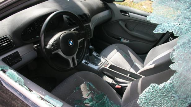 Die Scheibe eines BMW wurde eingeschlagen; Glassplitter liegen im Innenraum.