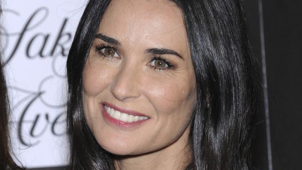 Nahaufnahme von Demi Moore mit dunklem, glänzendem Haar und einem strahlenden Lächeln.