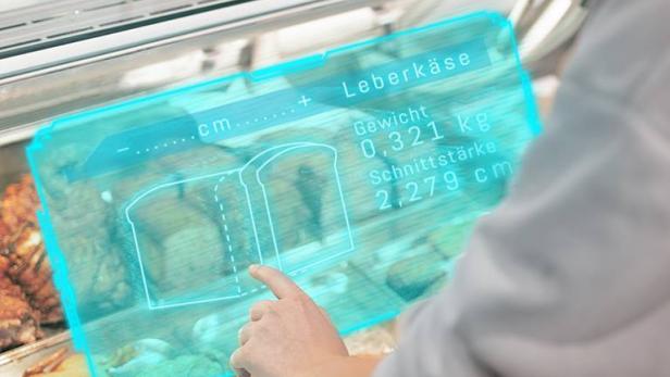 Eine Person bedient eine futuristische Leberkäse-Schneidemaschine bei Billa.