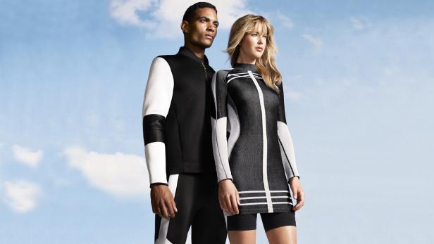 Ein Mann und eine Frau präsentieren futuristische Sportbekleidung vor blauem Himmel.