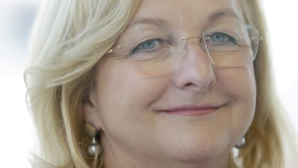 Porträt einer lächelnden Frau mit blonden Haaren und Brille.