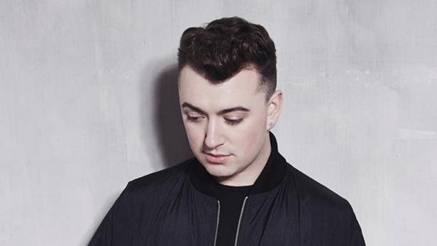Porträt des britischen Sängers Sam Smith vor einer grauen Wand.