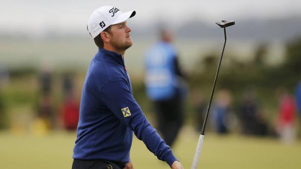 Ein Golfspieler mit Mütze hält einen Putter und blickt nach oben.