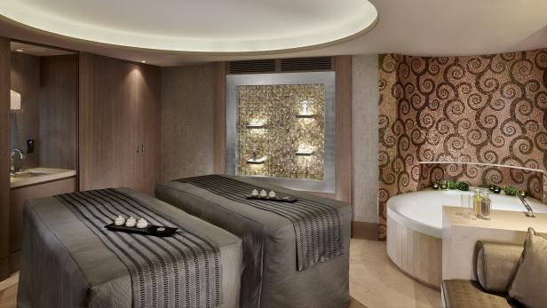 Ein luxuriöses Spa mit zwei Massageliegen und einem Whirlpool.