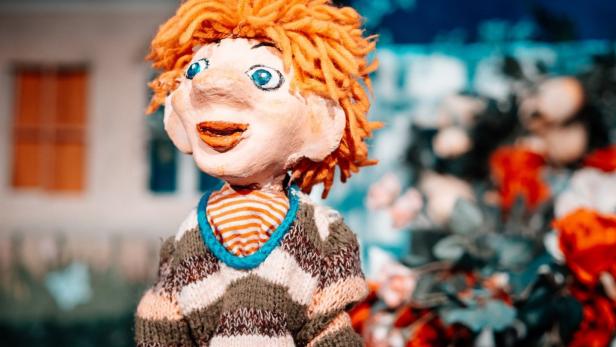 Eine handgefertigte Puppe mit orangefarbenen Haaren und einem gestreiften Pullover.