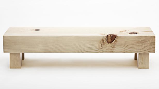 Eine einfache Holzbank mit sichtbaren Astlöchern vor einem weißen Hintergrund.