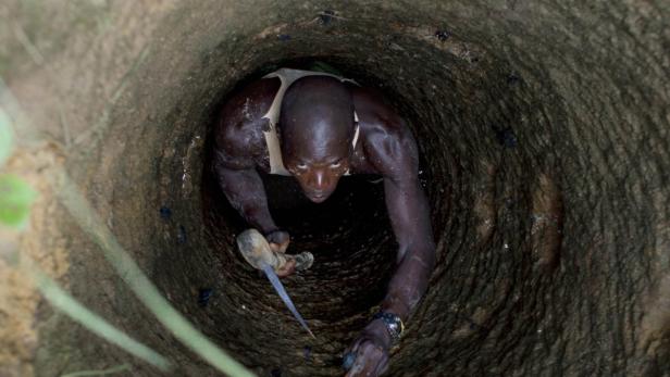 Ein Mann steigt in einen dunklen Brunnen hinab.
