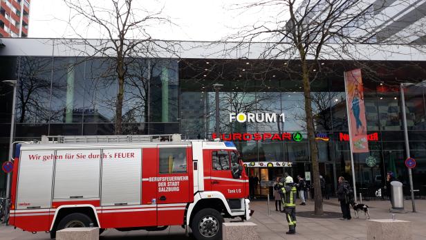 Ein rotes Feuerwehrfahrzeug der Berufsfeuerwehr Salzburg vor dem Forum 1 Einkaufszentrum.