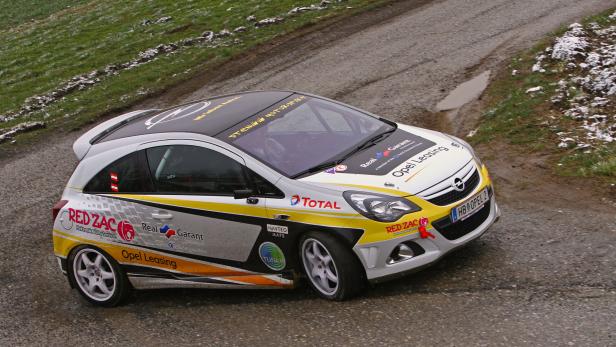 Ein Opel Corsa Rallye-Auto fährt auf einer schlammigen Straße.