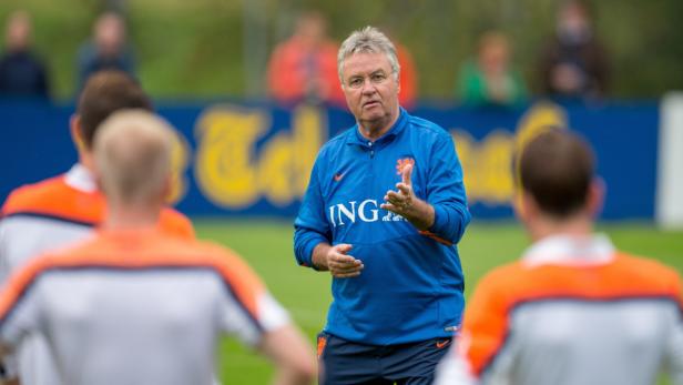 Ein Trainer in blauer Trainingsjacke spricht zu einer Gruppe von Fußballspielern.