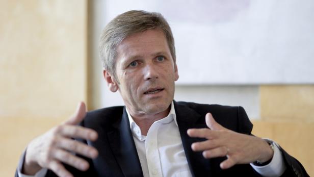 Ein Mann in Anzug und Hemd gestikuliert mit beiden Händen.