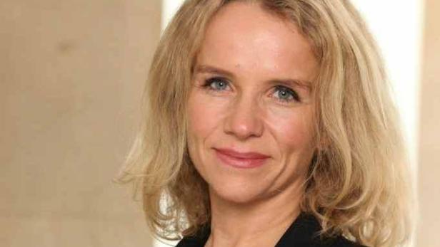 Porträt einer Frau mit blonden Haaren und einem schwarzen Blazer.