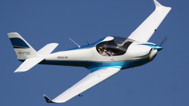 Ein weißes und blaues Skyleader 600 Flugzeug fliegt am blauen Himmel.