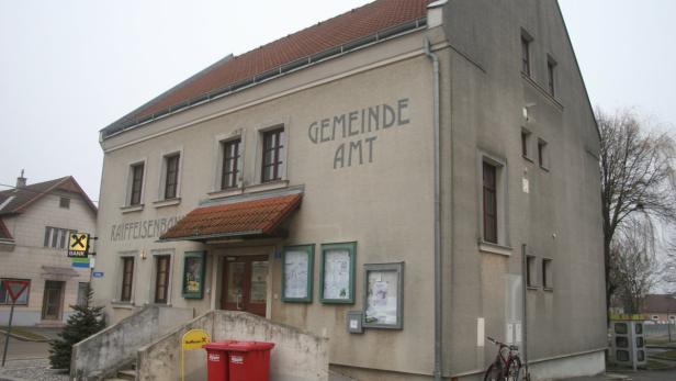 Das Gebäude des Gemeindeamts und einer Raiffeisenbank an einer Straße.