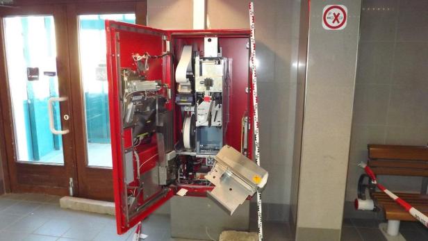 Ein aufgebrochener roter Fahrkartenautomat steht in einem Bahnhof.