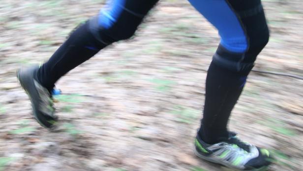 Beine einer Person in Laufkleidung und -schuhen in Bewegung.