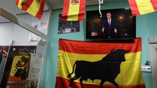 Spanish flags are are seen next to a TV screen showing Spanish Prime Minister and Socialist Worker's Party candidate Pedro Sanchez during a live televised debate ahead of general elections in Madrid