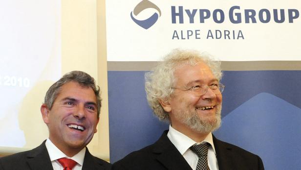 Zwei Männer lächeln vor einem Banner der Hypo Group Alpe Adria.