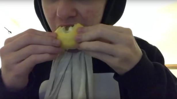 Hier isst ein Jugendlicher eine Zitrone mit Schale.